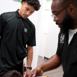The Barbering Academy instructor coaches a student mid-fade during the 2025 Back to School community event.