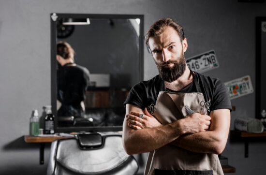 Skilled barber holding clippers and scissors confidently.